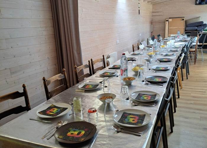 Salle commune avec les tables dressées pour le repas d'un groupe