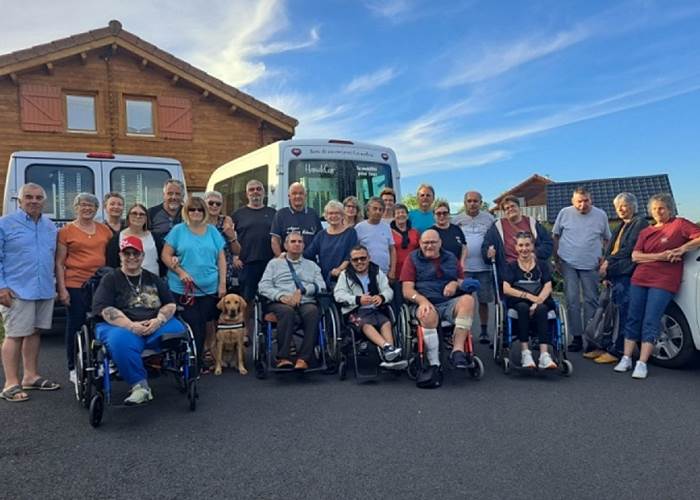 Groupe de personnes handicapées avec leurs accompagnants devant un gîte