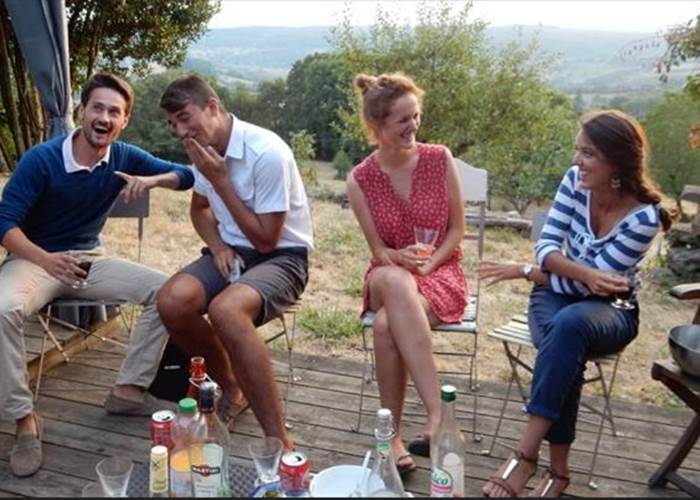 Groupe d’amis profitant d’un moment convivial en terrasse d’un gîte à Noailhac en Corrèze, vue sur la campagne près de Collonges-la-Rouge