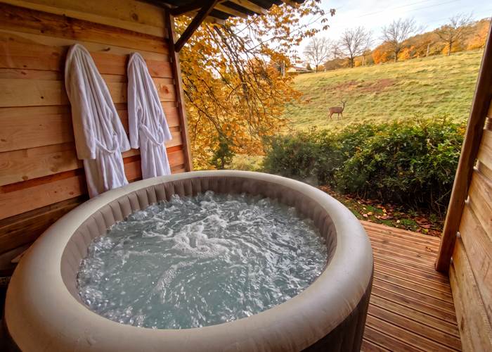 Bain à remous extérieur abrité avec vue sur la prairie et les arbres d'automne à Vitrac en Dordogne