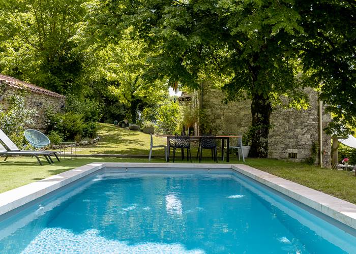 Table extérieure avec vue sur la piscine et le jardin arboré