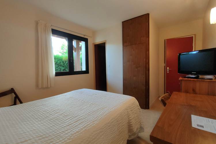 Vue d’ensemble de la Chambre 5 avec lit double, bureau et télévision