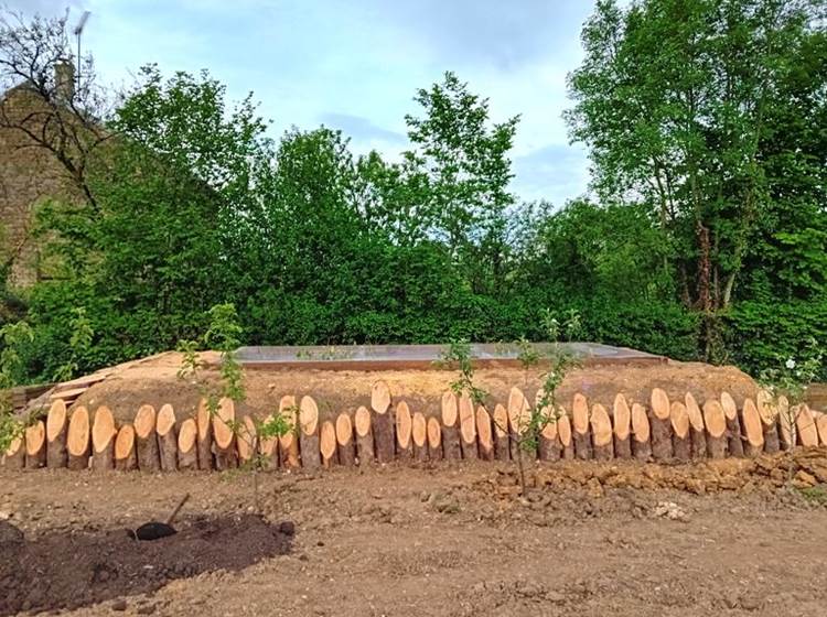 Habillage du plus grand bassin de phytoépuration avec des rondins de mélèze