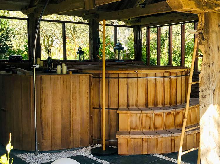 un grand bain en cèdre rouge abrité sous un joli préau