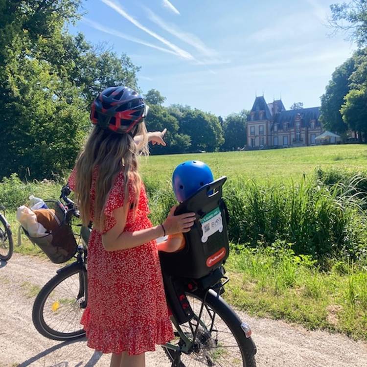Cycliste et son enfant devant cha^teau