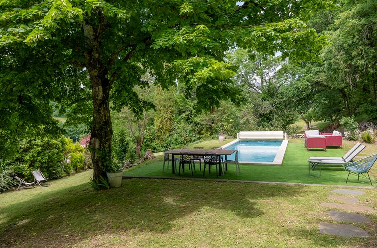 Table extérieure avec vue sur la piscine et le jardin arboré