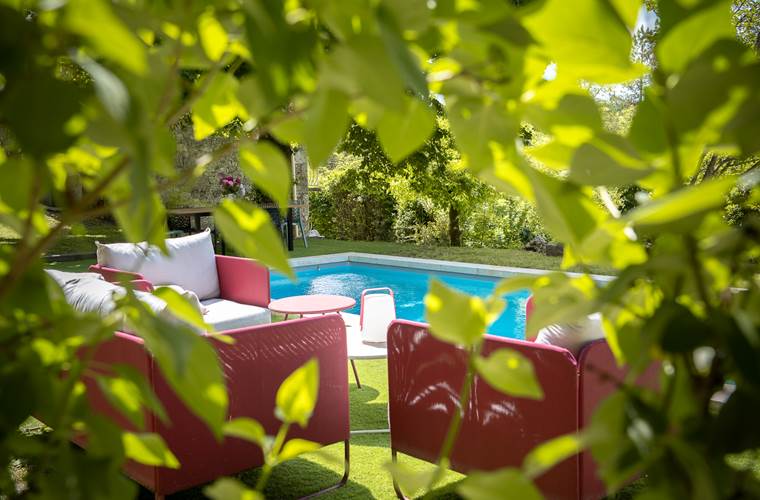 Salon extérieur face à la piscine dans un cadre naturel