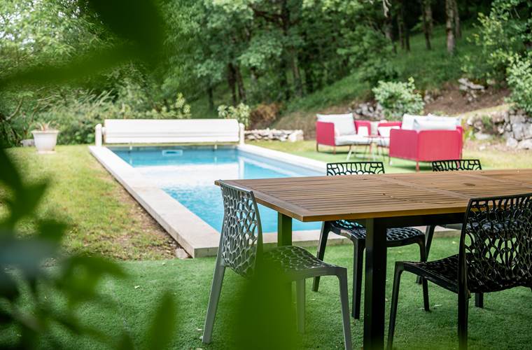 Table extérieure avec vue sur la piscine et le jardin arboré