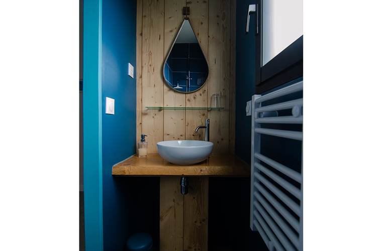 La salle de bain avec son lavabo et un radiateur sèche- serviettes. Le savon est fourni