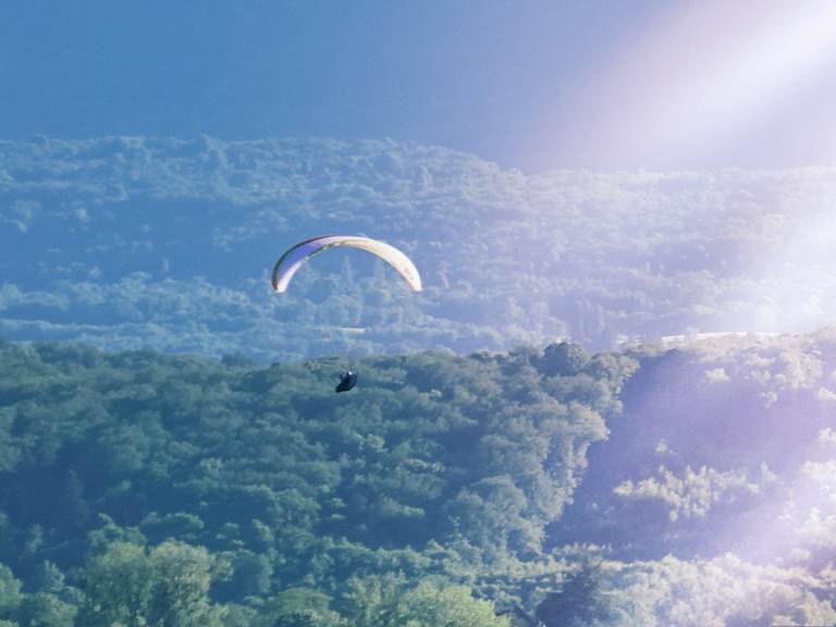 Vol en parapente au-dessus du Manoir du Colombier, gîte 4 étoiles dans le Bugey avec vue sur les montagnes.