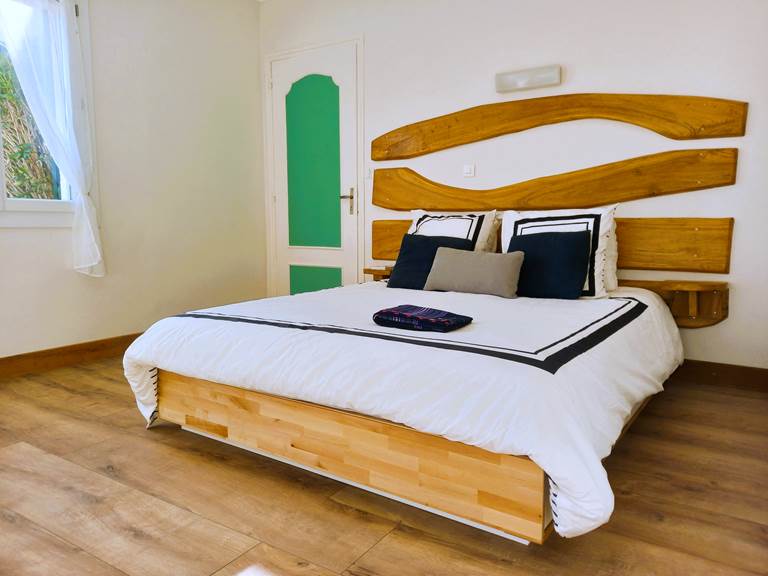 Chambre double lit queen size avec tête de lit bois sculpté, parquet chaud et literie blanche – chambre de charme Lauzerte Quercy Blanc