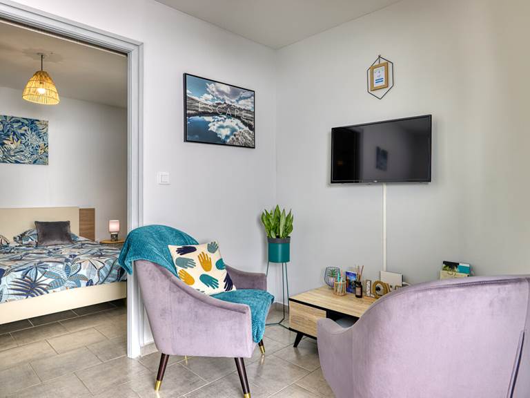 Petit salon du Cocon d’Hell-Bourg avec deux fauteuils confortables et télévision, idéal pour se détendre après une journée de découverte à Salazie.