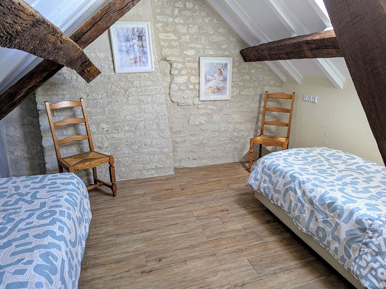 Kids bedroom with peaked celing and exposed beams at Tuffeau Sunsets, Jaulnay Gites de Famille features two single beds.