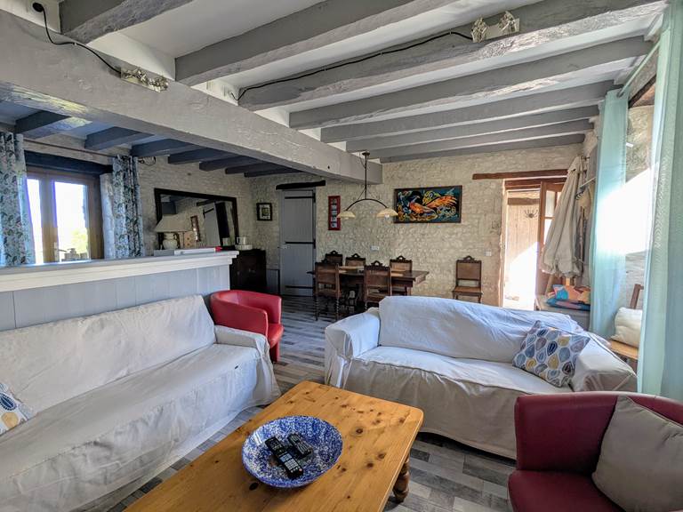 The open concept living and dining room at Tuffeau Sunsets, Jaulnay Gites de Famille features comfortable couches with the dining table in the background.