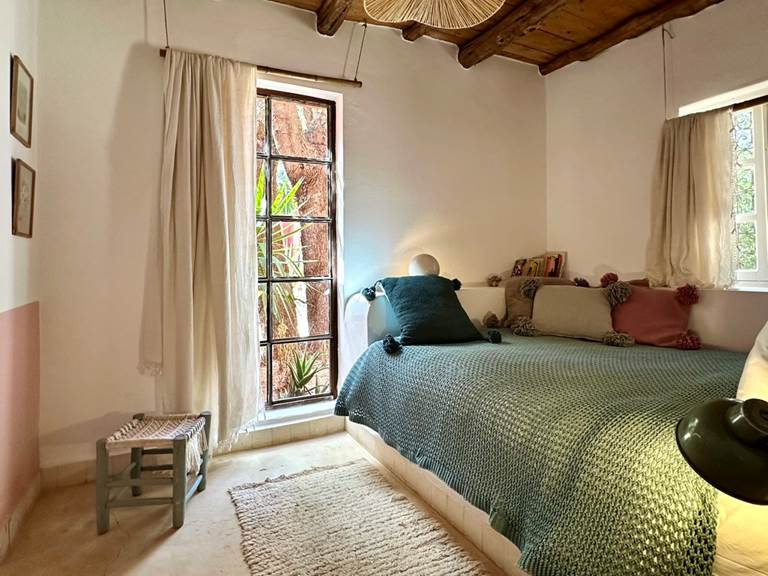 Le lit de la seconde chambre de la Suite Warda est lovée dans la pièce, entre les fenêtres de lumières et de verdure....