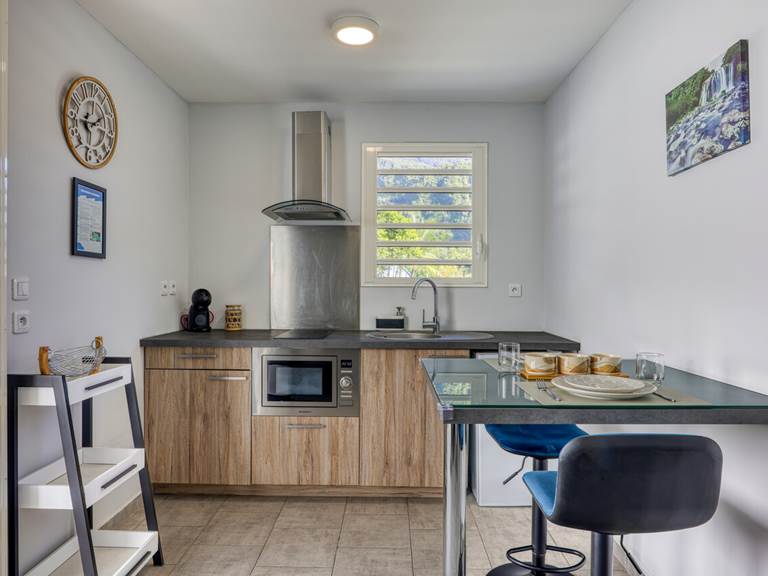 Espace cuisine et coin repas du Cocon d’Hell-Bourg, entièrement équipé et offrant une vue dégagée sur le Piton des Neiges, au cœur du cirque de Salazie.