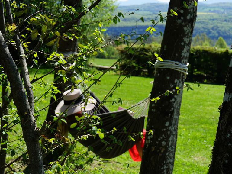 Fille dans un hamac face aux montagnes du Bugey, dans une location de vacances près du Grand Colombier, à 1h de Genève, Annecy et 1h20 de Lyon