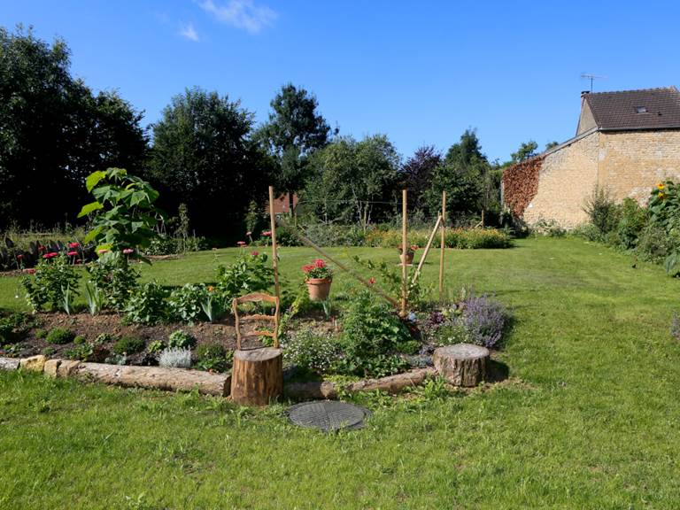 Un tapis de vivaces, juste en face de la terrasse. Au fond, le potager.