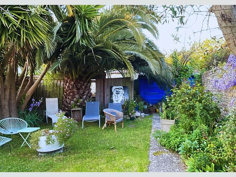 Jardin serein et ombragé : votre pause fraîcheur sous les palmes Entre ombre et lumière, ce coin jardin est un appel au repos. Mobilier confortable, végétation luxuriante et ambiance calme pour un séjour en toute quiétude à La Flotte.