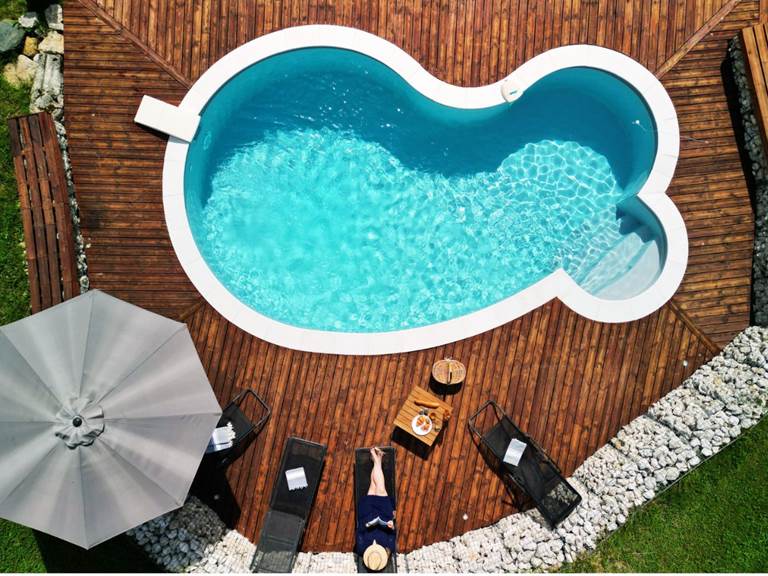 Piscine extérieure du Manoir du Colombier avec vue sur les montagnes du Bugey et cadre verdoyant.