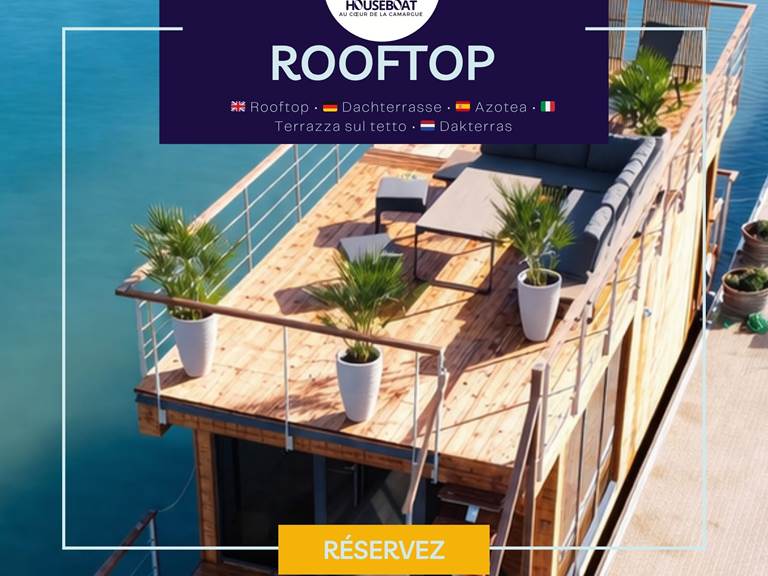 Grand rooftop avec salon extérieur et transats, offrant un espace de détente idéal avec vue dégagée sur l’eau et le paysage environnant.