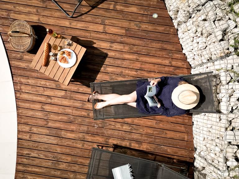 Relaxation sur les transats au bord de la piscine du Manoir du Colombier, gîte 4 étoiles avec terrasse en bois et vue sur le Bugey.
