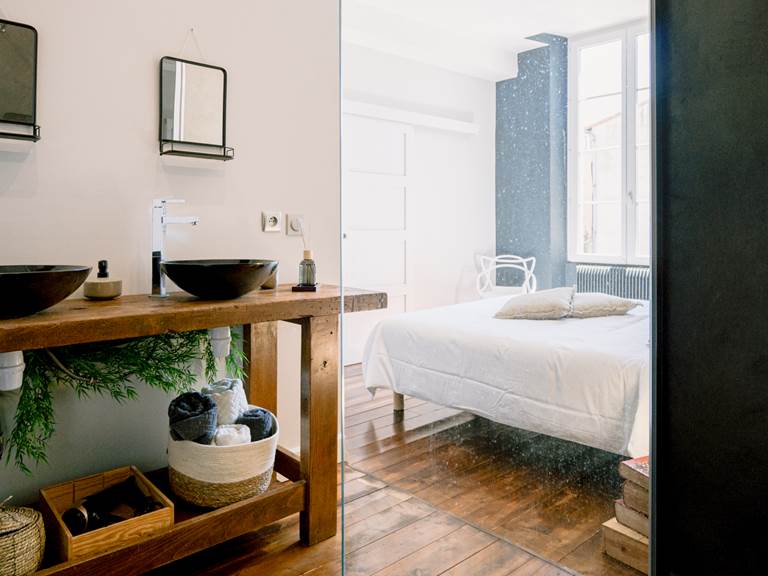 douche a` l'italienne ouvrant sur un vieil e´tabli qui accueille deux vasques, les miroirs et les serviettes et sur la chambre lumineuse, au parquet de bois d'e´poque et son lit king size