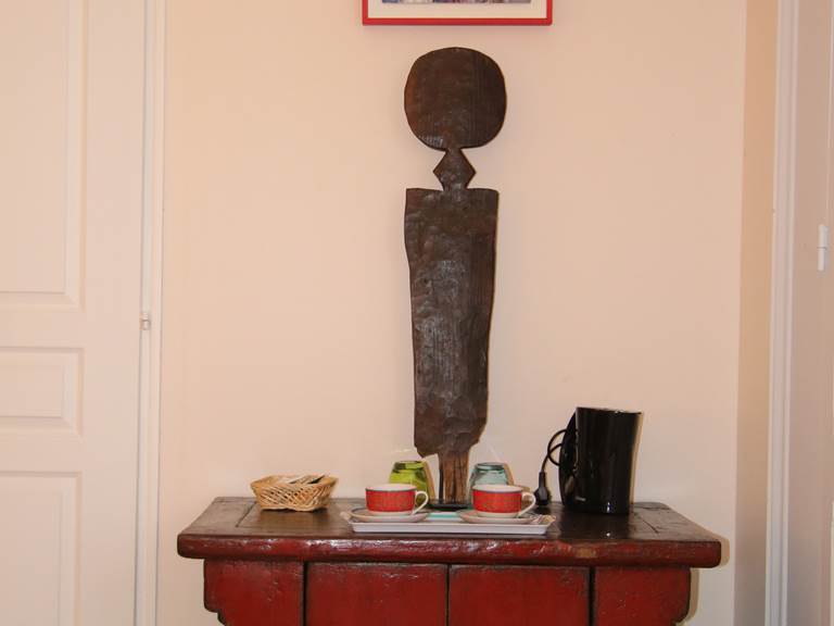 Le plateau de courtoisie de la chambre Bougainvillée. Cette statuette africaine et ce petit tableau d'un marché au Sénégal accompagnent votre plateau de courtoisie : verres pour l'eau du mini-bar, tasses, bouilloire, sachets de café, thé et tisane, sucre sont à votre disposition.