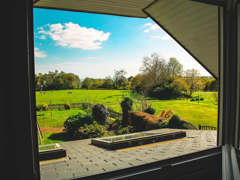 Côté Sud : Vue de la chambre sur la campagne, les chevaux et la baie de La Forêt-Fouesnant et au loin les îles Glénan selon météo