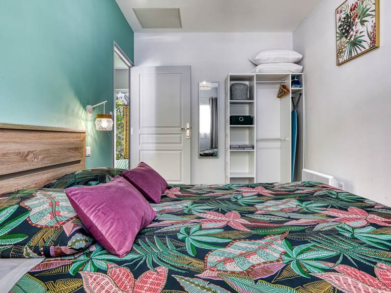 Chambre de l’appartement Bambou à Hell-Bourg, avec literie queen size et décoration tropicale pour un séjour relaxant à Salazie, La Réunion.