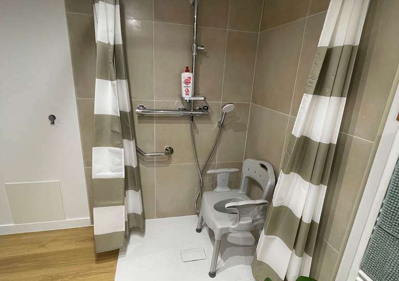 Douche à l'italienne avec barre de maintien et chaise à disposition