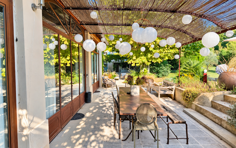 "la terrasse de la suite de l'Orangerie, à l'ombre des lanternes et ouverte sur le jardin"