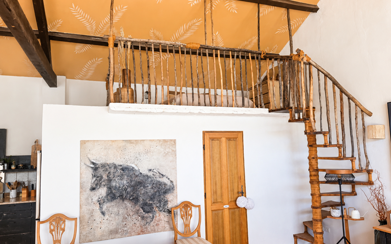 "la mezzanine de la suite de l'Orangerie, un espace nuit plein de charme sous les poutres, accessible par son escalier en bois"