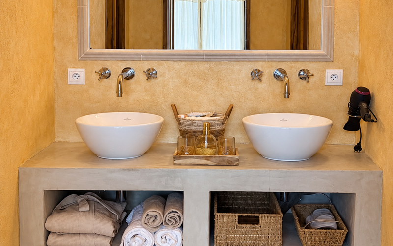 "La salle de bain de la suite de l'Orangerie, avec double vasque et une atmosphère douce aux tonalités naturelles"