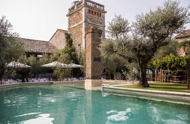 Grande piscine extérieure dans une cour fermée bordée d’oliviers centenaires