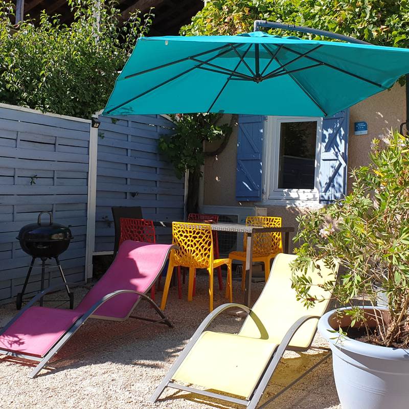 Terrasse devant le gîte, salon de jardin avec transats, parasol,  barbecue.