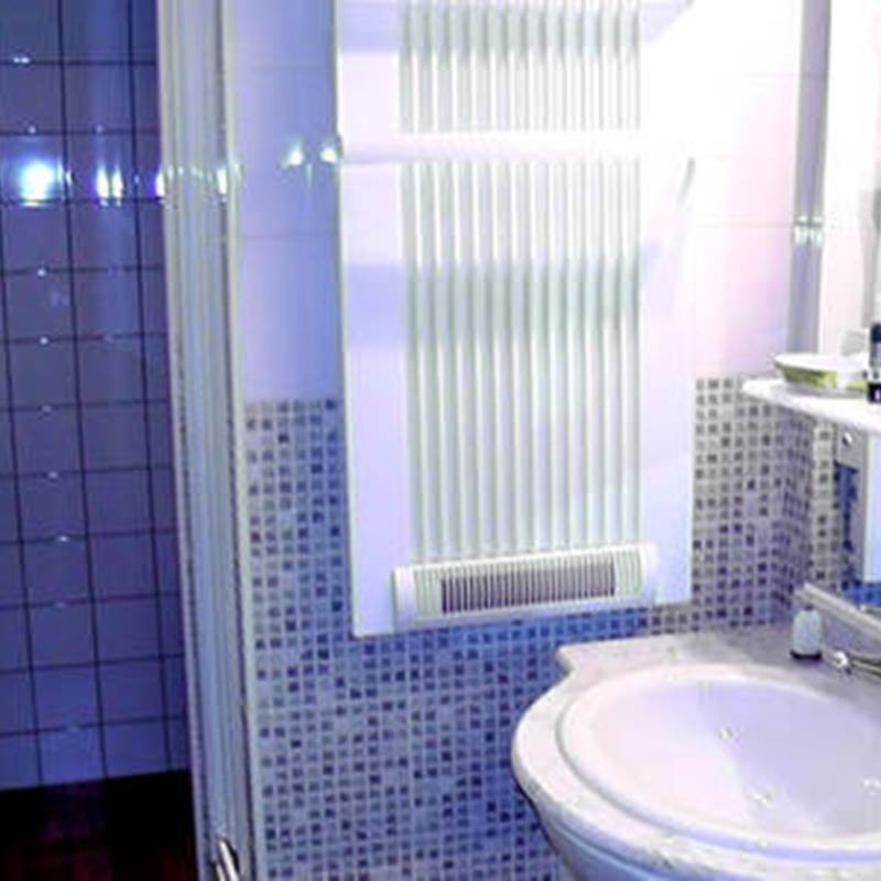 Salle d'eau avec cabine de douches, vasque, sèche serviettes, sèche cheveux, articles de toilette.