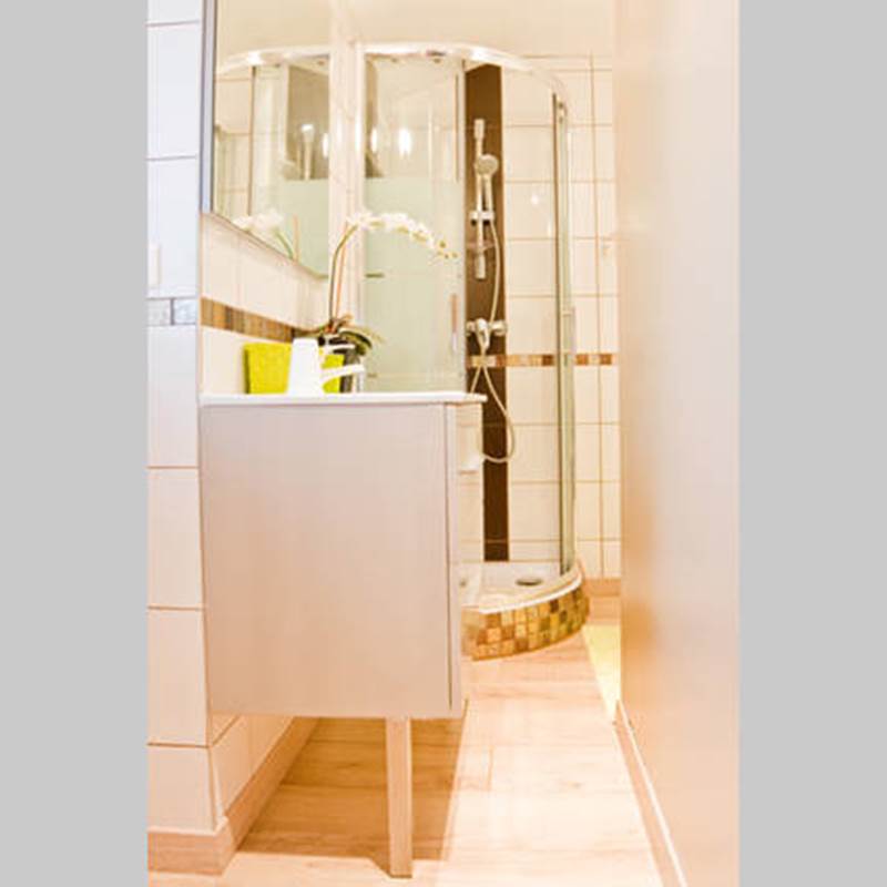 Salle de bain avec cabine de douche, vasque, articles de toilettes, sèche-cheveux, sèche serviettes.
