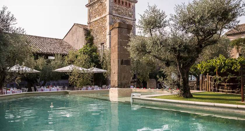 Grande piscine extérieure dans une cour fermée bordée d’oliviers centenaires