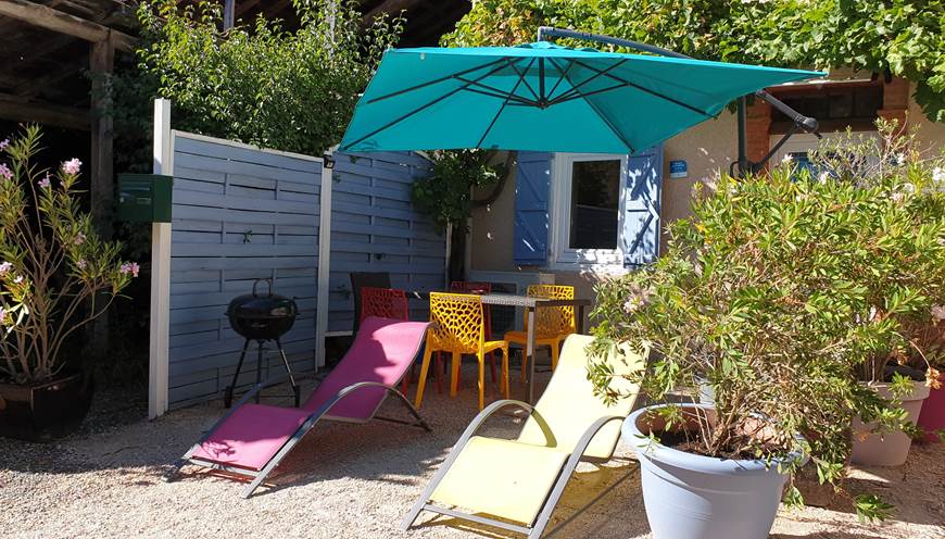 Terrasse devant le gîte, salon de jardin avec transats, parasol,  barbecue.