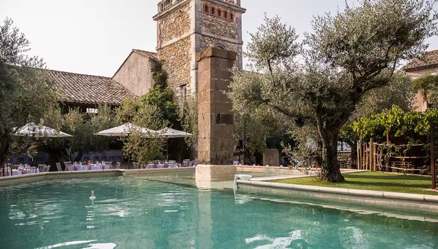 Grande piscine extérieure dans une cour fermée bordée d’oliviers centenaires