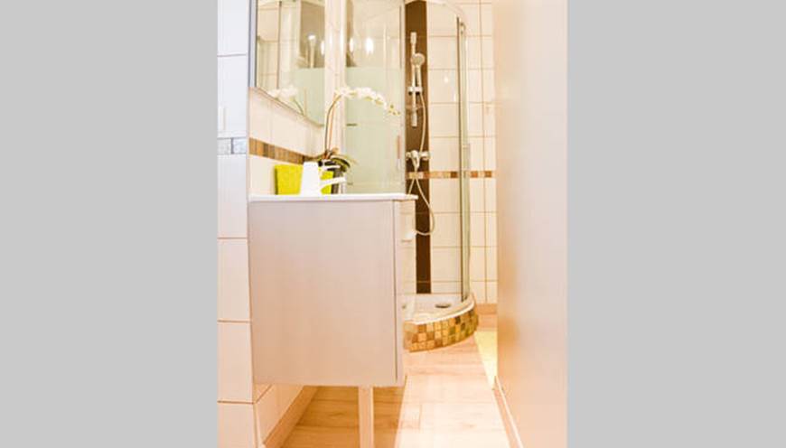 Salle de bain avec cabine de douche, vasque, articles de toilettes, sèche-cheveux, sèche serviettes.