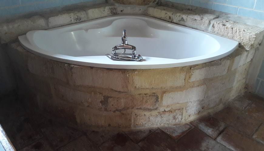 salle de bain avec baignoire d angle entouré de pierre de taille