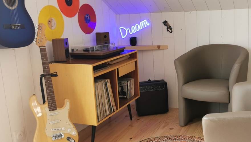 Espace musical coloré avec vinyles et guitares, parfait pour des loisirs créatifs et relaxation au Lodge de Kerescar à Plouarzel