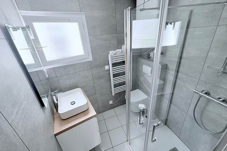 Maison Réthaise 2 – Salle d’eau lumineuse Espace soigné avec équipements modernes et rangements, pensé pour votre bien-être au cœur du centre-village.
