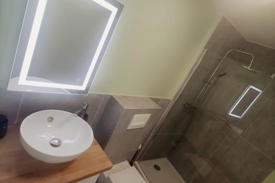 Salle d’eau contemporaine dans un esprit épuré Miroir rétroéclairé, vasque élégante et douche italienne : un espace bien pensé pour votre confort quotidien.