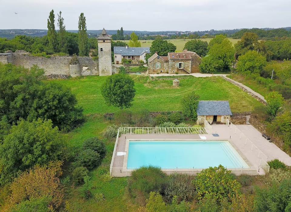 Maisons XVIIIe avec piscine et ruines d’un château médiéval en arrière-plan.